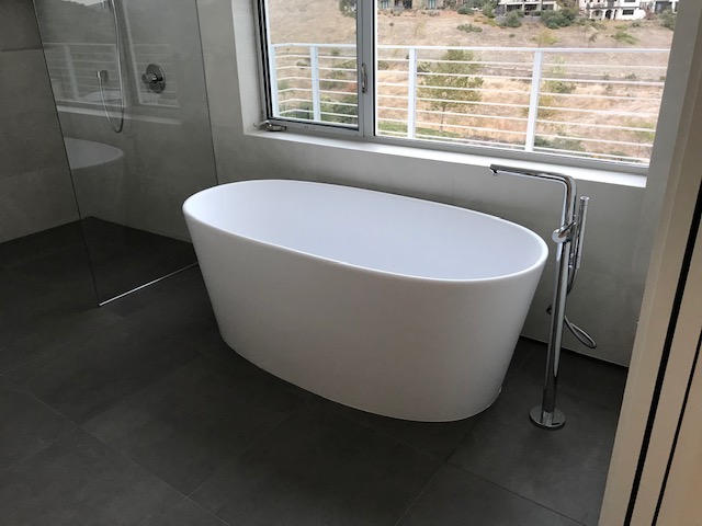A Bath Tub Near The Window And Standing Tap